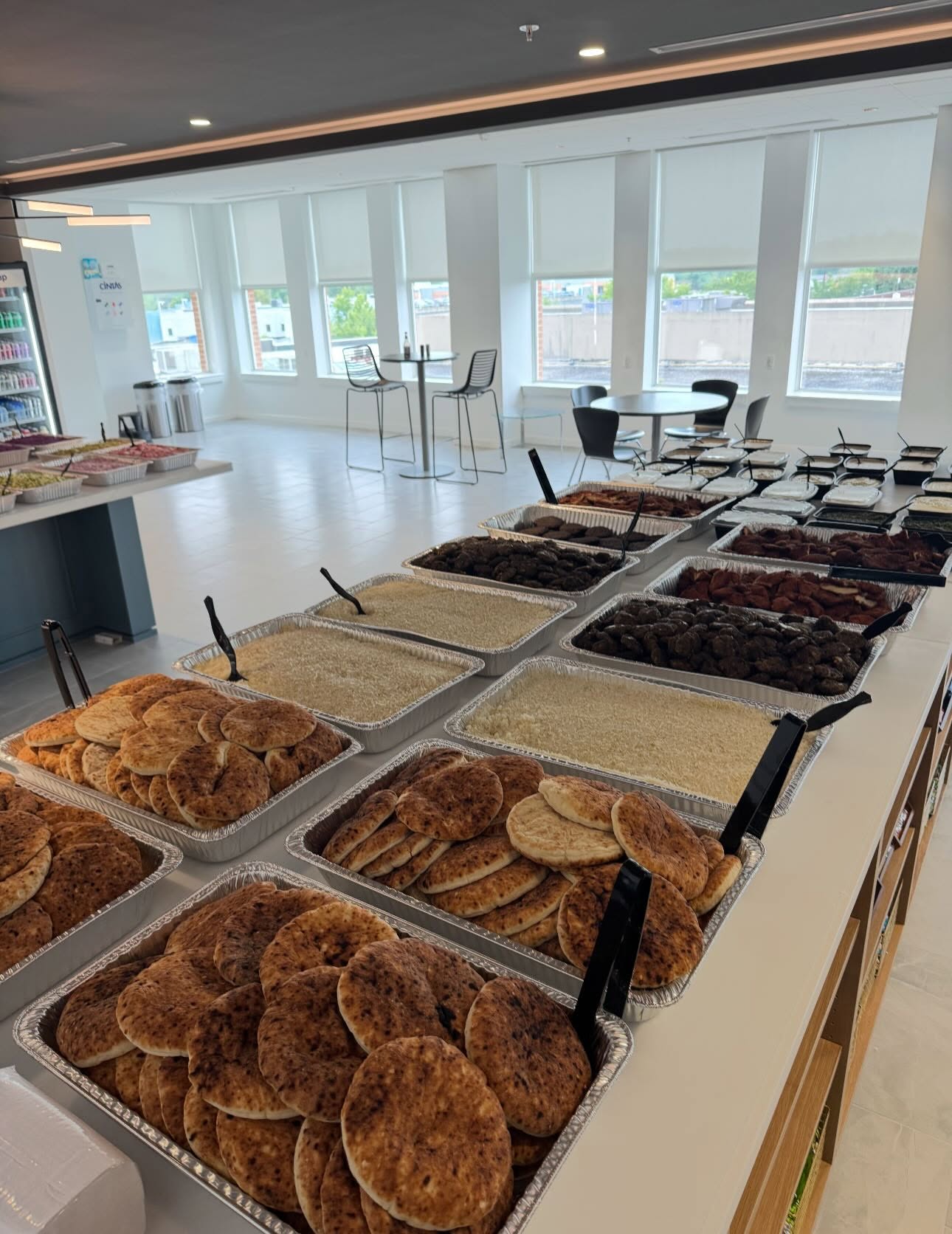Catering trays of fresh pita, rice, falafel, meats and sauces set up buffet style