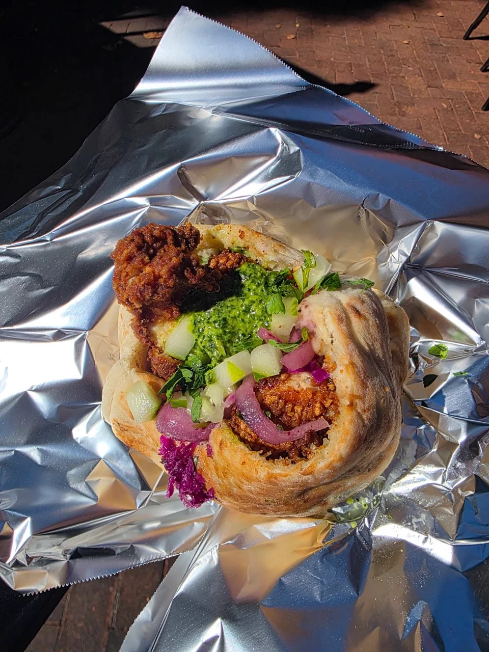 Stuffed pita with crispy chicken schnitzel, zhoug, cucumber, pickled onion and purple cabbage